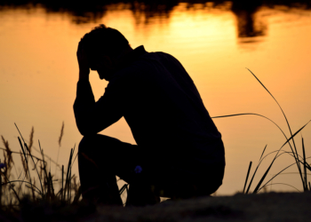 depressed man sitting against the light reflected in the water