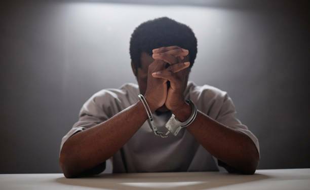 African American young man wearing handcuffs crying in remorse as criminal arrested, copy space