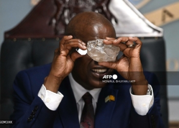 Botswana's President Mokgweetsi Masisi looks at a large diamond discovered in Botswana at his office in Gaborone on August 22, 2024. - The 2492 carat diamond was discovered in the Karowe mine in Botswana of Lucara Diamond Company. Botswana is one of the world's largest producers of diamonds, which constitute its main source of income, representing 30% of GDP and 80% of its exports. (Photo by Monirul BHUIYAN / AFP)