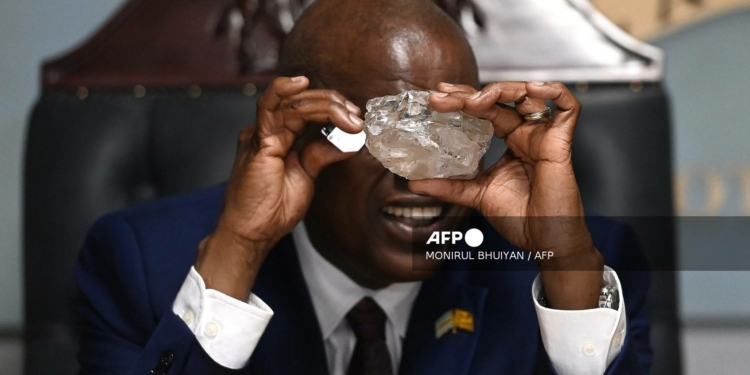 Botswana's President Mokgweetsi Masisi looks at a large diamond discovered in Botswana at his office in Gaborone on August 22, 2024. - The 2492 carat diamond was discovered in the Karowe mine in Botswana of Lucara Diamond Company. Botswana is one of the world's largest producers of diamonds, which constitute its main source of income, representing 30% of GDP and 80% of its exports. (Photo by Monirul BHUIYAN / AFP)