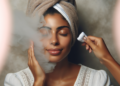 A woman with a towel draped over her head, enjoying a DIY steam facial at home.