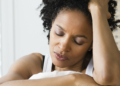 Mid adult woman sitting on the bed and suffering from a headache