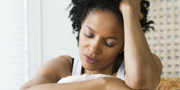 Mid adult woman sitting on the bed and suffering from a headache