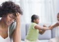 Stock Photo: Worried mom and kids fighting in the background