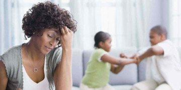 Stock Photo: Worried mom and kids fighting in the background